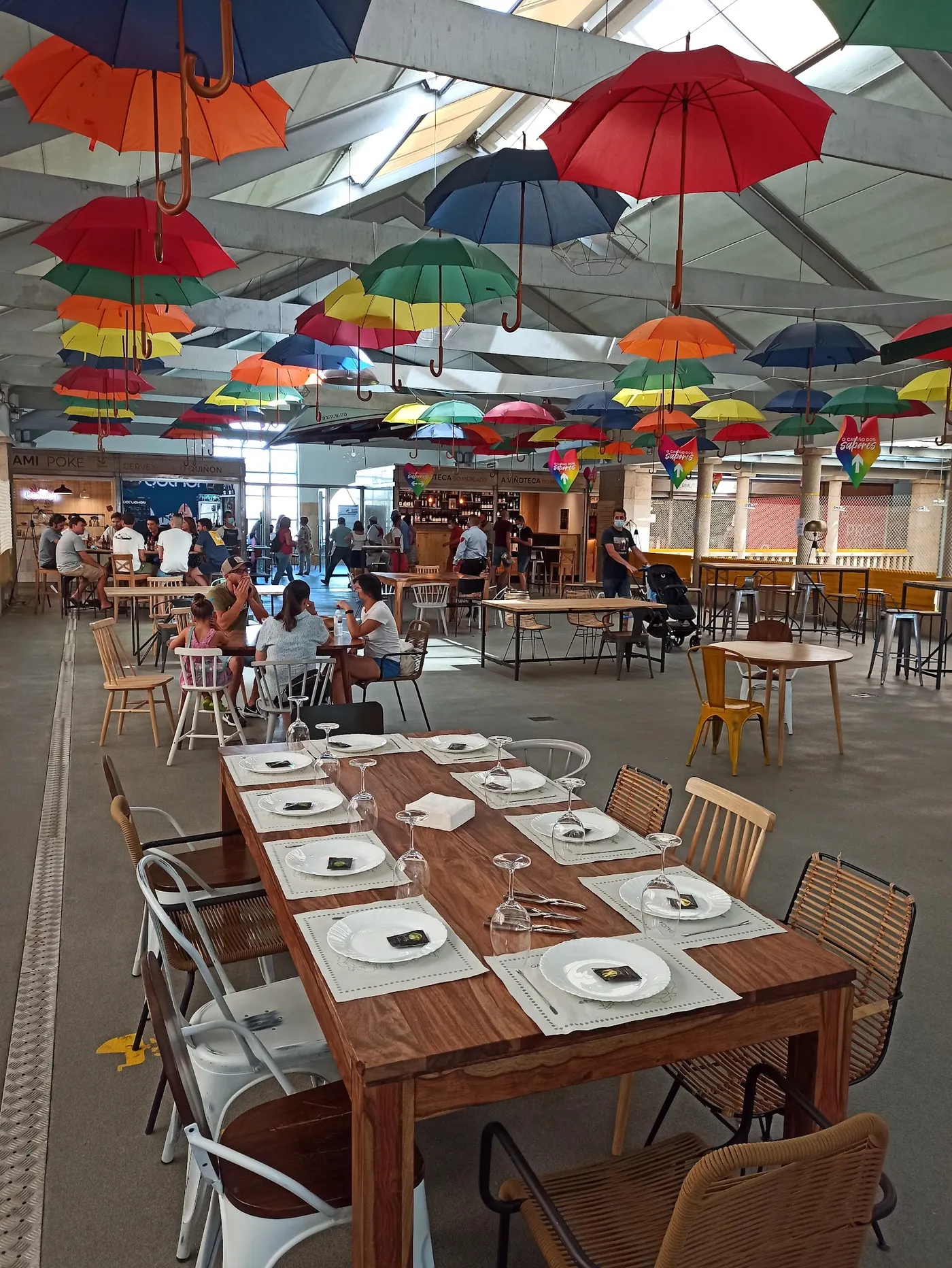 Mesa larga bajo los paraguas de colores del gastroespacio del mercado