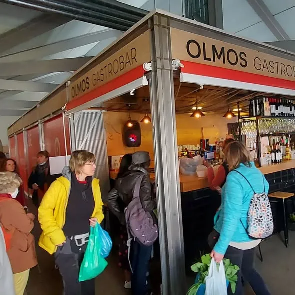 Clientas pasando frente al puesto de Olmos en el mercado
